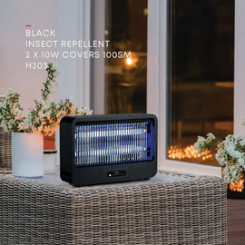 Black insect repellent on a table with flowers and a window in the background