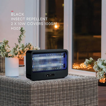 Black insect repellent on a table with flowers and a window in the background