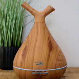 Wooden diffuser on a wooden surface with a plant in the background
