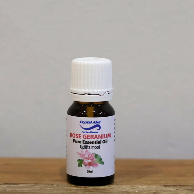Bottle of Rose Geranium essential oil on a wooden surface with a gray background